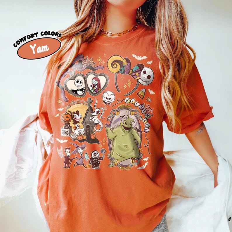 May include: Orange Comfort Colors t-shirt featuring a variety of cartoon characters and imagery from The Nightmare Before Christmas. The shirt includes the text "Comfort Colors" and "Yam" in an oval. The shirt has short sleeves.