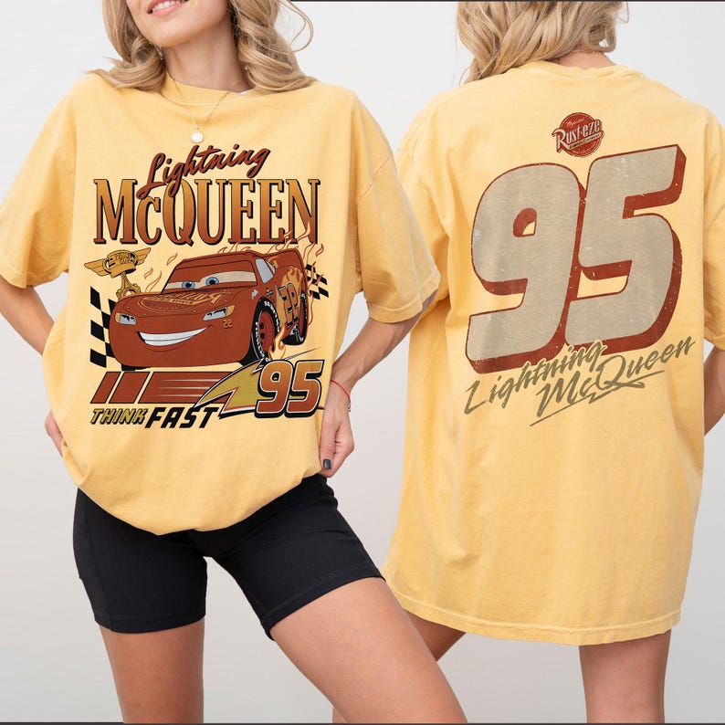 May include: Mustard yellow t-shirt with Lightning McQueen design. The front shows the character, the text "Lightning McQueen", and "Think Fast". The back has a large "95" and "Lightning McQueen" text. A fun, casual top.