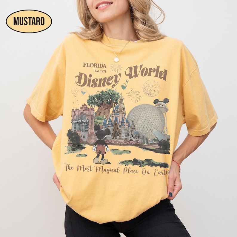 Puede incluir: Camiseta de color mostaza con un gr&aacute;fico de Disney World. El dise&ntilde;o incluye a Mickey Mouse, el nombre del parque de Florida y la frase "The Most Magical Place On Earth". La camiseta tiene un aspecto vintage y ligeramente descolorido.