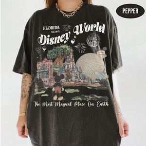 Puede incluir: Camiseta negra con un dise&ntilde;o de Disney World en Florida. El dise&ntilde;o incluye el texto "Florida Est. 1971 Disney World" y "The Most Magical Place On Earth". La imagen presenta a Mickey Mouse, un castillo y la Hollywood Tower.