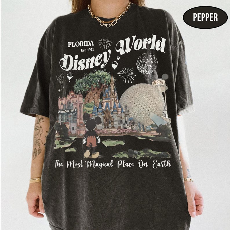 Puede incluir: Camiseta negra con un dise&ntilde;o de Disney World en Florida. El dise&ntilde;o incluye el texto "Florida Est. 1971 Disney World" y "The Most Magical Place On Earth". La imagen presenta a Mickey Mouse, un castillo y la Hollywood Tower.