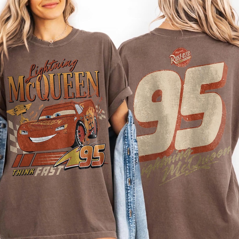 May include: Brown t-shirt featuring Lightning McQueen from the Cars film. The front graphic includes the character's image, the text "Lightning McQueen", and the number "95". The back displays a large "95" and the text "Lightning McQueen".