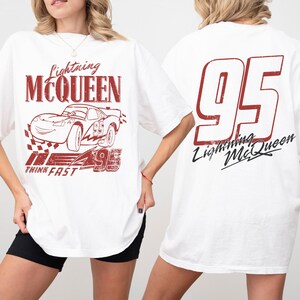Puede incluir: Camiseta blanca con un gr&aacute;fico rojo de Lightning McQueen, un coche de carreras de la pel&iacute;cula Cars. El dise&ntilde;o frontal incluye el texto "Lightning McQueen", una ilustraci&oacute;n de coche y "Think Fast". La parte trasera muestra un gran "95" y "Lightning McQueen".