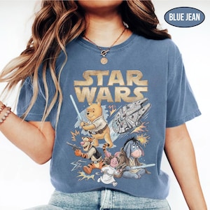 Puede incluir: Camiseta azul vaquero con un gr&aacute;fico de Star Wars con personajes de Winnie the Pooh. El dise&ntilde;o incluye a Winnie the Pooh con un sable de luz, Tigger con un blaster y otros personajes con el Halc&oacute;n Milenario.