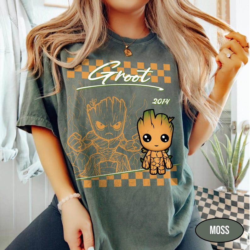 Puede incluir: Camiseta verde musgo con un gr&aacute;fico de Groot. El dise&ntilde;o incluye la palabra "Groot" sobre una imagen de dibujos animados de Groot, con el a&ntilde;o "2014" debajo. La camiseta tiene un patr&oacute;n de cuadros y un aspecto desgastado.