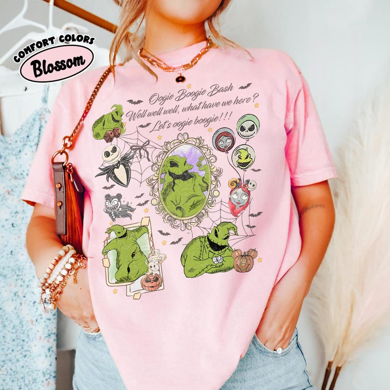 May include: Pink t-shirt with a graphic featuring Oogie Boogie and other characters from The Nightmare Before Christmas. The shirt includes the text "Oogie Boogie Bash" and "Let's oogie boogie!!!". The shirt is labeled "Comfort Colors" and "Blossom".