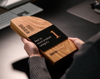 May include: A wooden award plaque with a black plaque on top. The wooden plaque has the text "2023" and "HOREA" engraved on it. The black plaque has the text "Best in wood product category" and "1" in a large font. The bottom of the plaque has the text "inko".