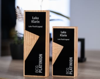 May include: Two wooden plaques with black and silver accents. The plaques feature the text "Luka Klarin" and "Lake Placid Legend". The text "BCG PLATINION" is also visible on the plaques.