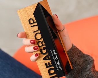 May include: A wooden and black award plaque with the text "IDEAGROUP" and "2024 Idea Group Brave Award" and "Jenifer Ginger".