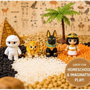 May include: A set of four small figurines including a white mummy, a gold lion, a black jackal with a blue collar, and a character in a white dress with a gold headdress, accompanied by a plastic palm tree and a small pyramid model.