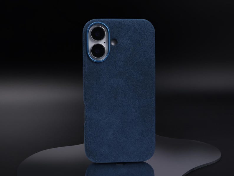 May include: A dark blue phone case with a suede texture and a camera lens cutout.