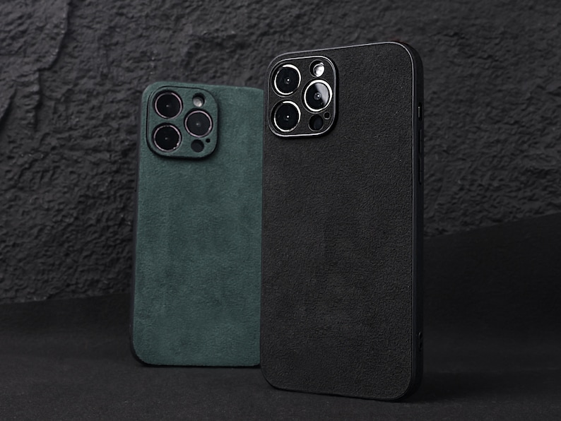 May include: Two phone cases, one black and one green, with a suede-like texture. Both cases have a raised camera bump with multiple camera lenses.