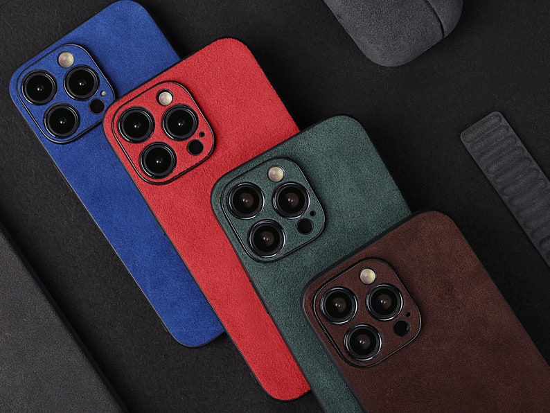 May include: Four different coloured phone cases with a suede texture. The cases are blue, red, green, and brown.