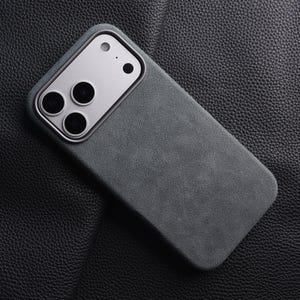 May include: A dark gray phone case with a silver camera module. The case has a textured surface and a rectangular shape. The camera module has three large lenses and two smaller ones.