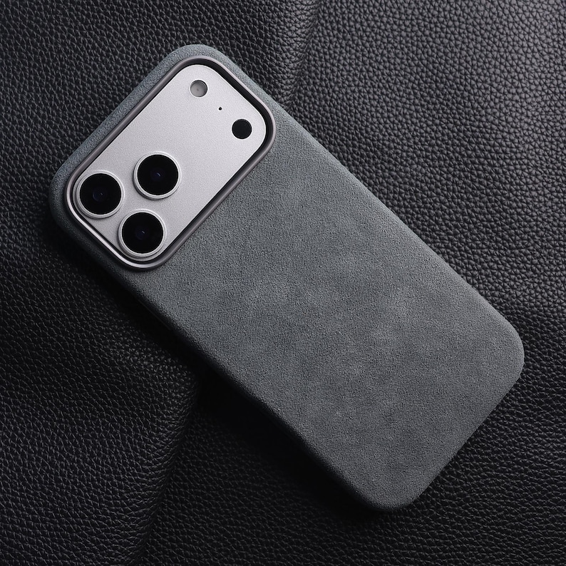 May include: A dark gray phone case with a silver camera module. The case has a textured surface and a rectangular shape. The camera module has three large lenses and two smaller ones.