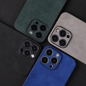 May include: Four different coloured phone cases with a camera lens cutout. The cases are green, grey, black, and blue.