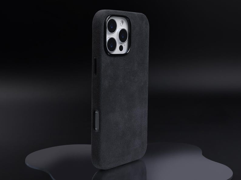 May include: A black phone case with a textured, suede-like finish. The case has a raised camera bump with three lenses.