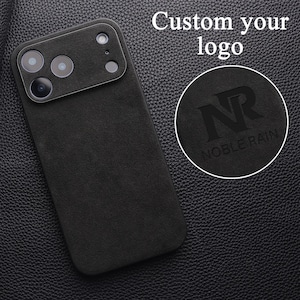 Op de afbeelding: Een zwarte, getextureerde telefoonhoes met een uitsparing voor de camera en een cirkelvormige inzet met een in reliëf aangebracht logo met de letters NR en de tekst NOBLE RAIN. De tekst Custom your logo is rechtsboven in beeld zichtbaar.