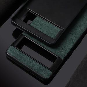 Pode incluir: Duas capas de telefone pretas com um material verde semelhante a camur&ccedil;a na parte de tr&aacute;s. As capas t&ecirc;m uma borda preta elevada ao redor das bordas.