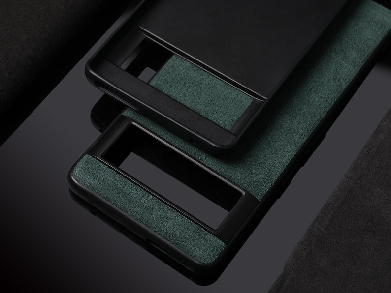 Pode incluir: Duas capas de telefone pretas com um material verde semelhante a camur&ccedil;a na parte de tr&aacute;s. As capas t&ecirc;m uma borda preta elevada ao redor das bordas.