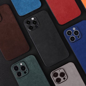 May include: Assortment of ten phone cases in various colours and textures. The cases are made of a soft, suede-like material and feature a raised camera bump. The cases are arranged in a grid pattern on a black background.