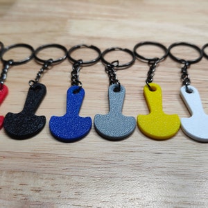 May include: A set of ten keychains with different coloured plastic charms shaped like a small shovel. The keychains are attached to silver key rings.