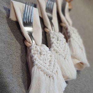 以下が含まれることがあります： フリンジ付きの白いクロシェのナプキンリングが付いた白いリネンナプキン3枚。ナプキンリングはハート型です。
