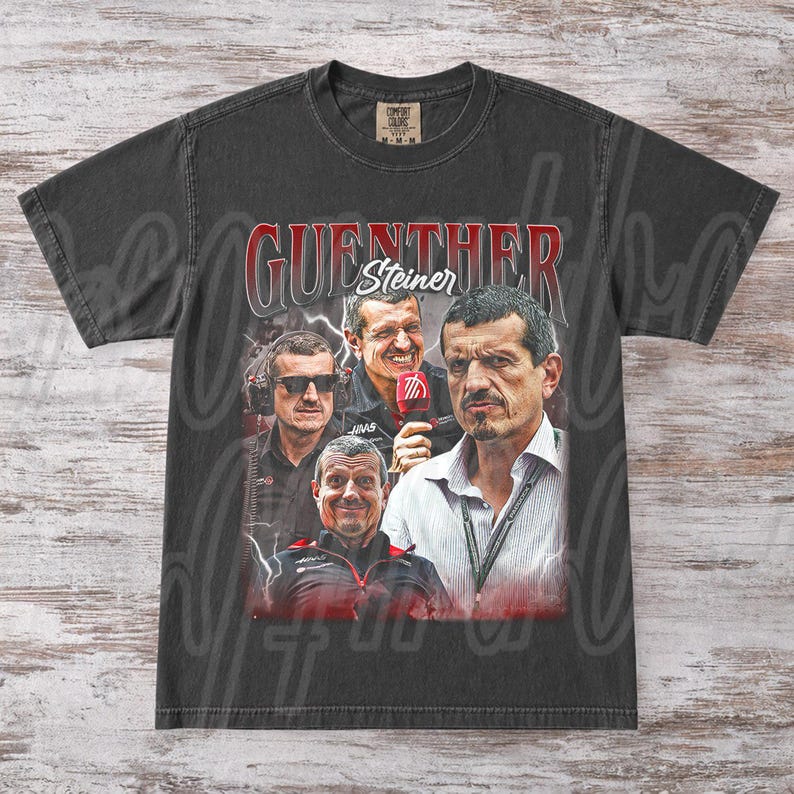 May include: Dark gray t-shirt featuring a collage of images of Guenther Steiner, with the name "Guenther Steiner" in red and white lettering. The shirt has a vintage, distressed look.