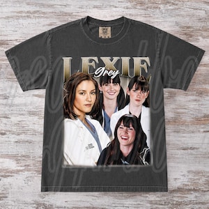 Puede incluir: Camiseta gris oscuro con un collage de cuatro mujeres y el texto dorado "LEXIE Grey". Las mujeres visten ropa médica. La camiseta tiene un aspecto vintage y desgastado.