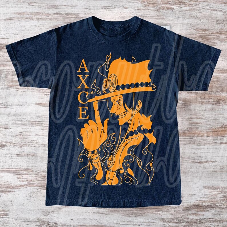 以下が含まれることがあります： ネイビーブルーのTシャツ。オレンジ色のイラストで、帽子と炎をまとったキャラクターが描かれています。「ACE」の文字がオレンジ色で縦にプリントされています。デザインはTシャツの中央に配置されています。