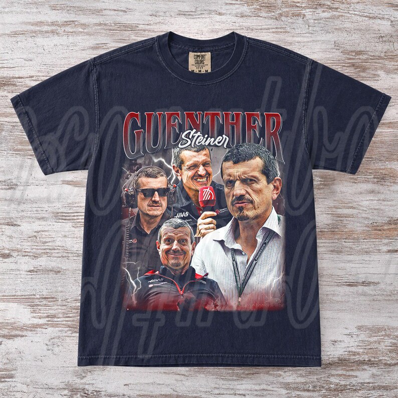 May include: Navy blue t-shirt featuring a graphic of G&uuml;nther Steiner, with his name in red and white. The design includes multiple images of Steiner. The shirt is from the Comfort Colors brand.