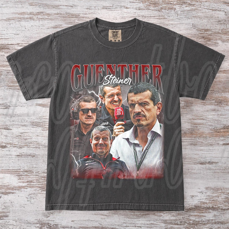 May include: Dark gray t-shirt featuring a collage of images of Guenther Steiner, with the name in red lettering. The shirt has a vintage look and feel, with a crew neck and short sleeves. The Comfort Colors tag is visible.