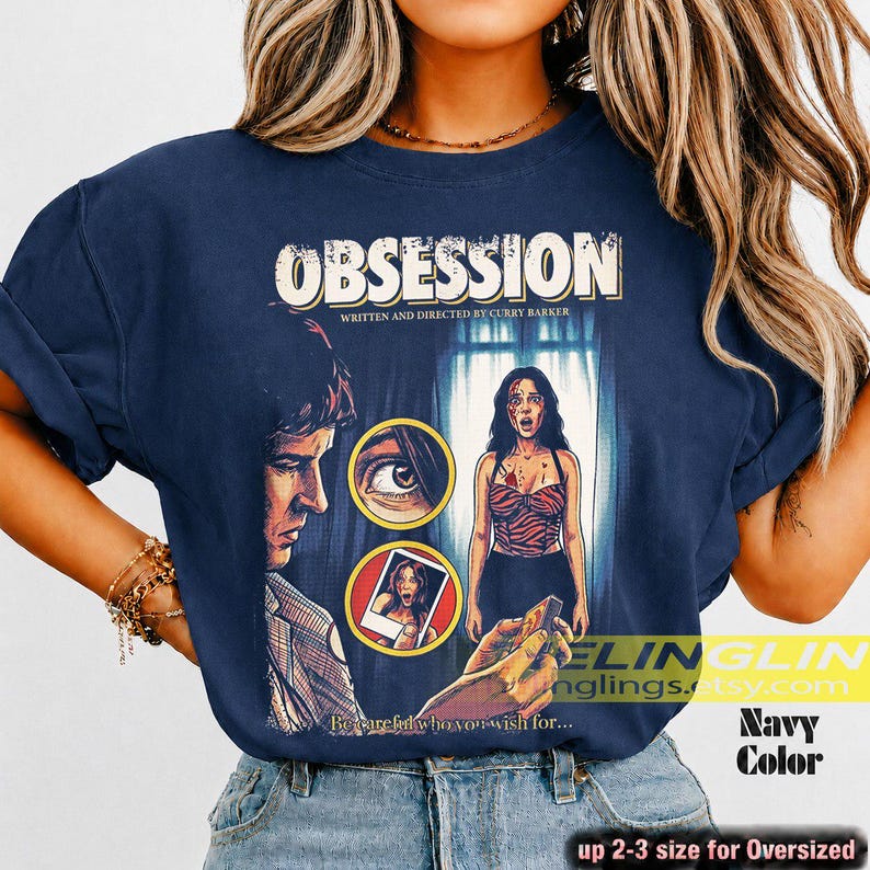 K&ouml;nnte beinhalten: Marineblaues T-Shirt mit dem Wort "OBSESSION" und einem Filmplakat-Grafik. Die Grafik zeigt einen Mann, eine Frau und den Text "WRITTEN AND DIRECTED BY CURRY BARKER." Das Shirt hat auch den Text "Beware who you wish for..." und "Navy Color."