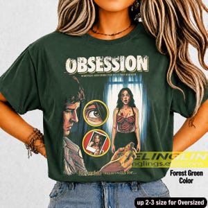 K&ouml;nnte beinhalten: Forstgr&uuml;nes &uuml;bergro&szlig;es T-Shirt mit dem Wort "OBSESSION" in einer Vintage-Schriftart. Das Shirt zeigt ein Filmplakat-Design mit einem Mann, einer Frau und dem Text "Written and Directed by Curry Barker". Der Text "Becarefid who you wish for..." ist ebenfalls sichtbar.