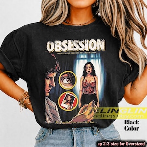 K&ouml;nnte beinhalten: Schwarzes T-Shirt mit einem Filmplakat-Design mit dem Wort "OBSESSION". Das Design zeigt einen Mann, eine Frau und den Text "WRITTEN AND DIRECTED BY CURRY BARKER". Das Shirt hat auch den Text "Becareful who you wish for..."