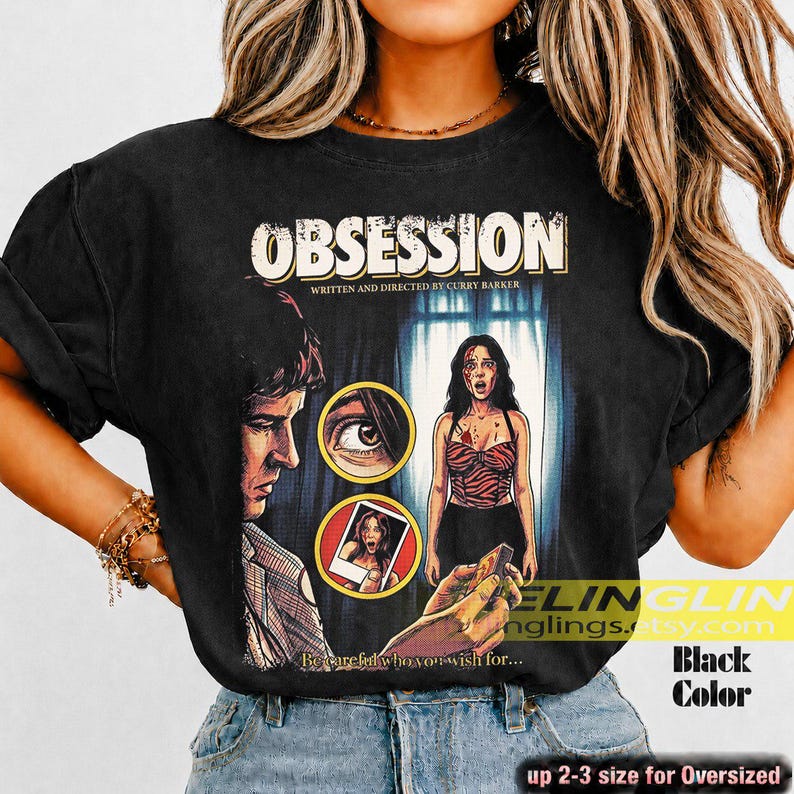 K&ouml;nnte beinhalten: Schwarzes T-Shirt mit einem Filmplakat-Design mit dem Wort "OBSESSION". Das Design zeigt einen Mann, eine Frau und den Text "WRITTEN AND DIRECTED BY CURRY BARKER". Das Shirt hat auch den Text "Becareful who you wish for..."