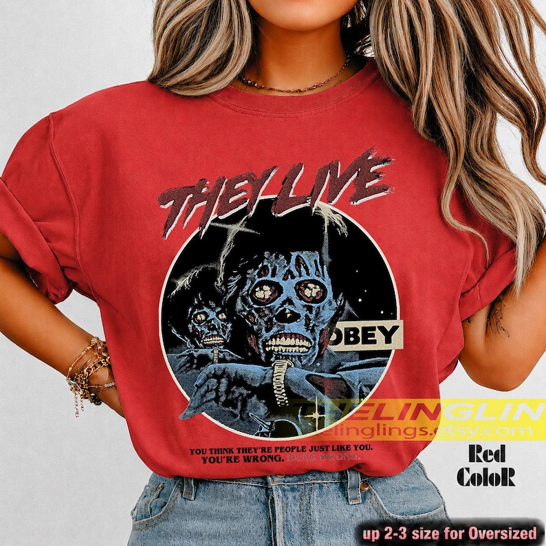K&ouml;nnte beinhalten: Ein rotes T-Shirt mit einem Grafikdruck aus dem Film They Live. Das Design zeigt einen schwarzen kreisf&ouml;rmigen Rahmen mit zwei blau get&ouml;nten Alien-Figuren, dem Text "THEY LIVE" oben, "OBEY" auf einem Balken und dem Zitat "YOU THINK THEY'RE PEOPLE JUST LIKE YOU. YOU'RE WRONG."