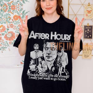 Può includere: T-shirt nero con il titolo del film "After Hours" a lettere bianche e un'immagine in bianco e nero del cast. La citazione, "Would you just give me a break? I really just want to go home," è stampata anche sulla maglietta.