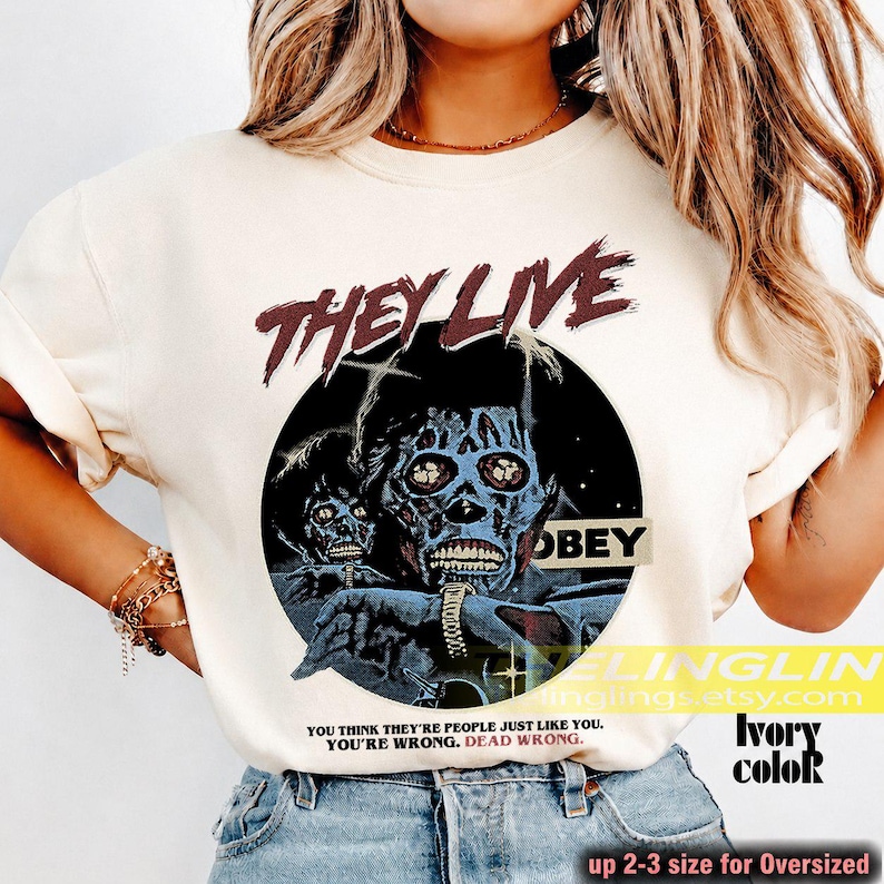 K&ouml;nnte beinhalten: Ein elfenbeinfarbenes T-Shirt mit einem Grafikdruck aus dem Film They Live. Das Design enth&auml;lt den Text THEY LIVE in Dunkelrot, eine kreisf&ouml;rmige Illustration einer Alien-Figur, das Wort OBEY und den Text YOU THINK THEY'RE PEOPLE JUST LIKE YOU. YOU'RE WRONG. DEAD WRONG.