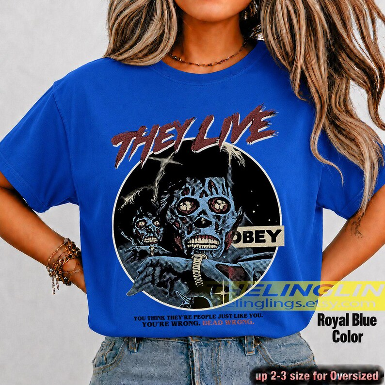 K&ouml;nnte beinhalten: Ein k&ouml;nigsblaues Kurzarm-T-Shirt mit einem Grafikdruck einer skelettierten Figur und dem Text THEY LIVE und OBEY. Unter der Grafik steht der Text: YOU THINK YOU ARE PEOPLE JUST LIKE YOU. YOU ARE WRONG. DEAD WRONG. Das Shirt hat einen Rundhalsausschnitt.