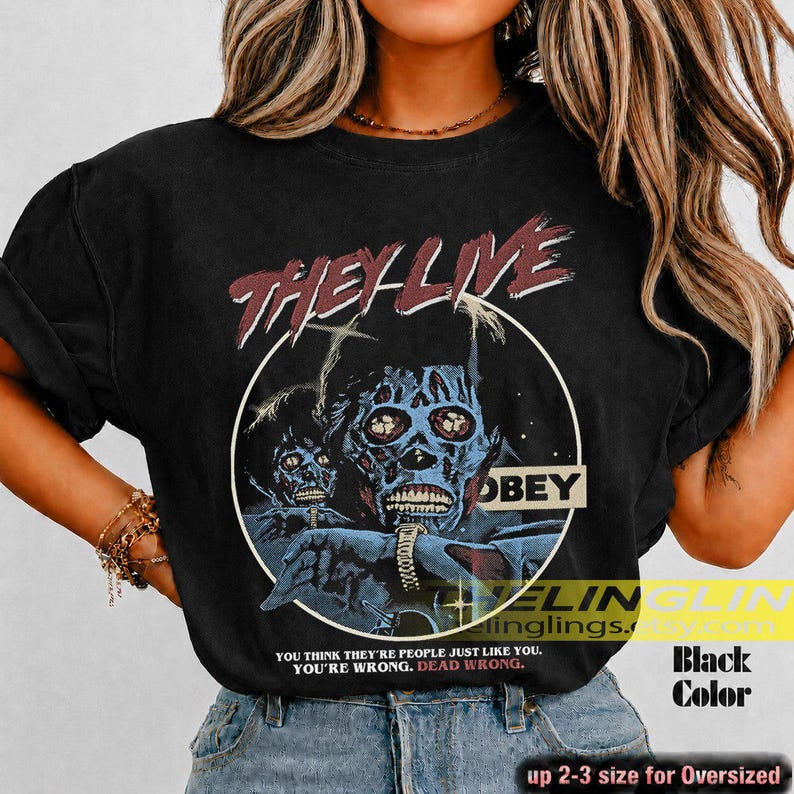 K&ouml;nnte beinhalten: Ein schwarzes Kurzarm-T-Shirt mit einem Grafikdruck aus dem Film They Live. Das Design zeigt eine blau get&ouml;nte Alien-Figur in einem wei&szlig;en Kreis mit dem Text They Live, Obey und You think they're people just like you. You're wrong. Dead wrong.