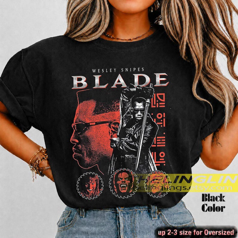 May include: A black short-sleeve t-shirt featuring a graphic print of Wesley Snipes as Blade. The design includes the text BLADE, a large profile portrait, a figure holding a sword, and three circular character icons in red and white.