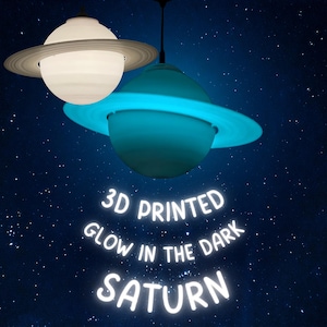Może przedstawiać: Dwie drukowane w 3D lampy wiszące w kształcie Saturna. Jedna jest biała, druga świeci na niebiesko. Każda ma pierścień wokół środka. Tekst "3D PRINTED GLOW IN THE DARK SATURN" znajduje się poniżej na tle gwiazd.