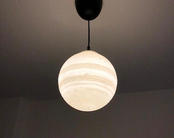May include: A spherical pendant light fixture featuring a white, textured, marbled surface that glows when illuminated. The globe is suspended from a thin black cord attached to a black circular ceiling canopy mounted on a plain ceiling.