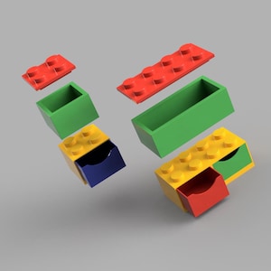May include: A set of colorful storage boxes shaped like Lego bricks. The boxes have drawers that slide out and lids that lift off. The boxes are red, yellow, green, and blue.