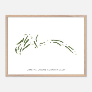 May include: A framed print featuring a green and white golf course map. The map shows the layout of Crystal Downs Country Club. The print is in a light-colored wooden frame, perfect for wall decor.