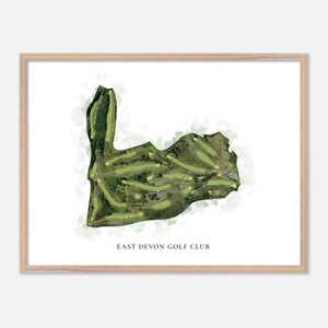 May include: A framed print of the East Devon Golf Club course map. The map is a watercolor-style illustration with green fairways and rough, set against a white background with green watercolor washes. The text "EAST DEVON GOLF CLUB" is printed at the bottom.