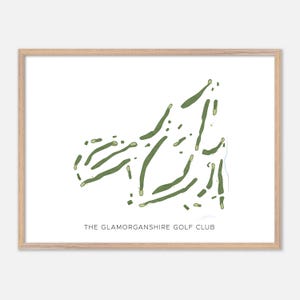 May include: A framed print featuring a green golf course map design on a white background. The map shows the layout of The Glamorganshire Golf Club. The frame is made of light-colored wood.