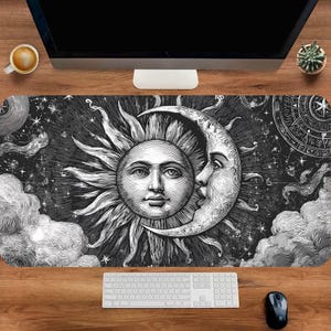May include: Black and white desk mat featuring a celestial design with a sun and moon face, clouds, and stars. The mat is rectangular and designed to fit under a keyboard and mouse, enhancing the workspace aesthetic.