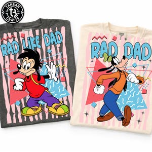 Peut inclure: Deux t-shirts avec des personnages de dessins animés et le texte "RAD LIKE DAD" et "RAD DAD". L'un est gris foncé avec Max, l'autre est crème avec Dingo. Les deux ont un design rétro des années 80 avec des formes géométriques.